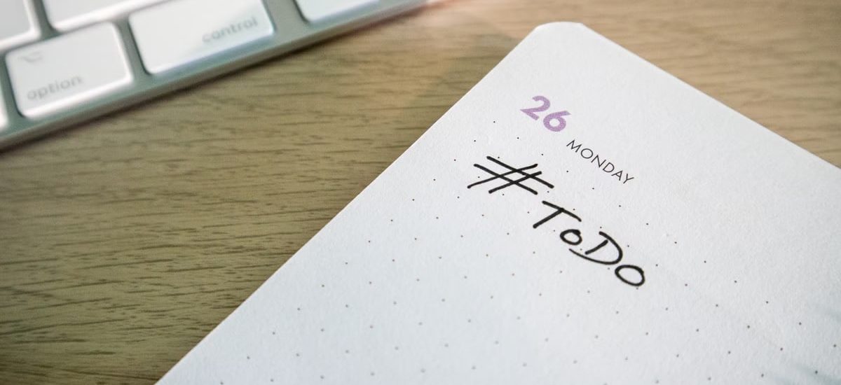 Close-up of a to-do list next to a computer keyboard on a desk.