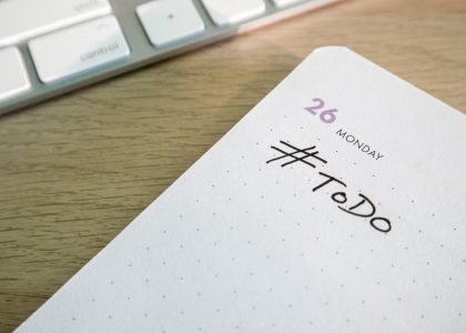 Close-up of a to-do list next to a computer keyboard on a desk.
